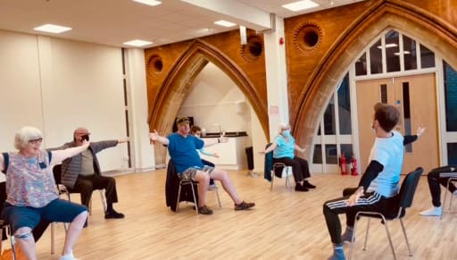 Picture of people making dance moves while seated